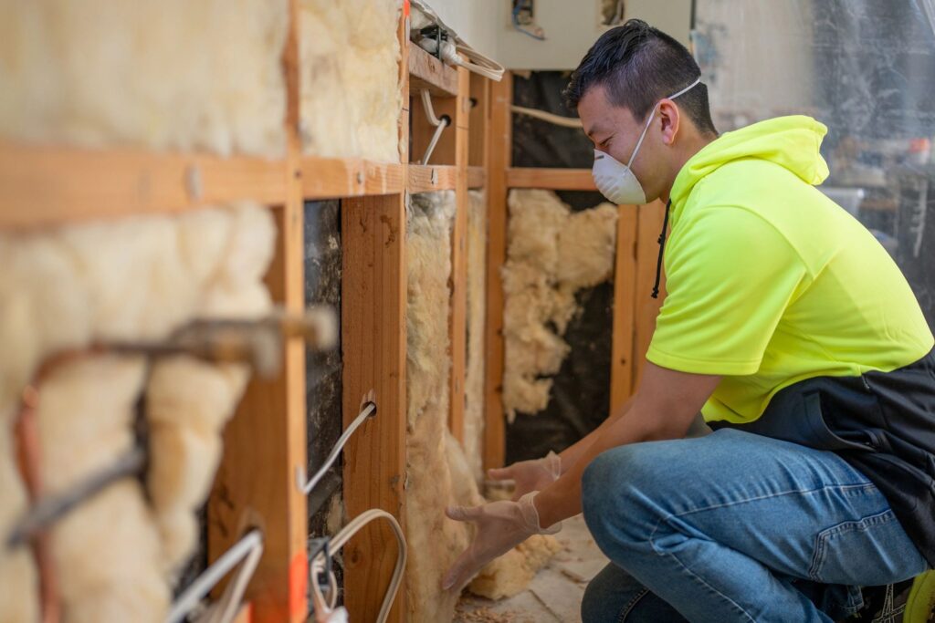Male Worker Installing Insulation In Residential Wall