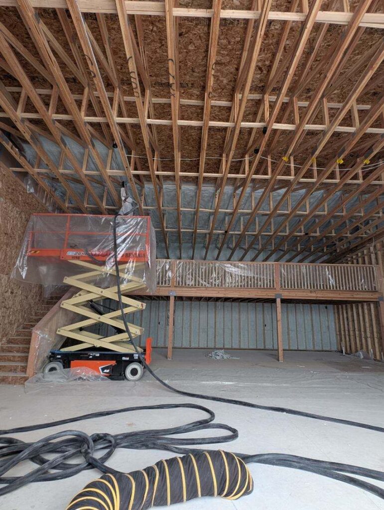 Contractor spraying closed-cell spray foam insulation inside a 16,000 square foot warehouse in Kalispell Montana.